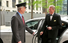 Man in a tuxedo exiting a chauffeured vehicle